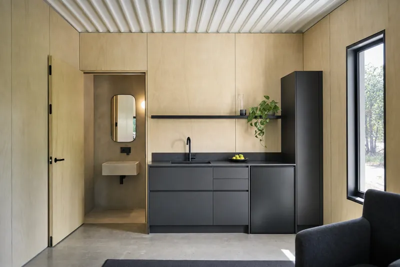 Kitchenette em antracite mate com bancada em pedra composta e porta do WC